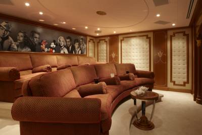 This luxurious home theater features plush seating and a captivating mural of classic Hollywood stars.