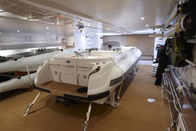A pristine white tender boat named "Lady Christine" rests in a yacht's spacious, well-lit tender bay.