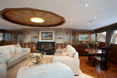 Luxurious yacht interiors feature plush seating, elegant artwork, and a polished wood dining area with a scenic ocean view.