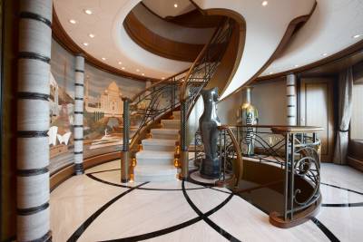A grand staircase with intricate metalwork and a stunning mural of world landmarks sets a luxurious tone.