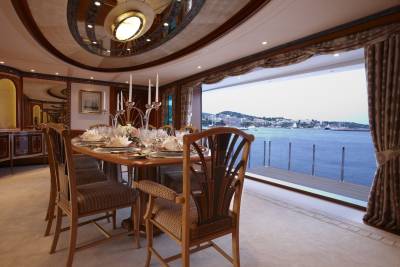 Dine in opulent style aboard this yacht, with a beautifully set table offering panoramic views of a Mediterranean coastline.