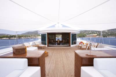 Luxurious yacht deck offers a serene dining area and lounge space with stunning views of the Mediterranean coastline.