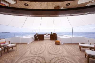 Luxurious yacht deck offers a serene escape with plush seating and a stunning ocean view under a retractable canopy.