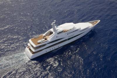 A luxurious white yacht glides through the deep blue ocean, leaving a frothy wake behind it.