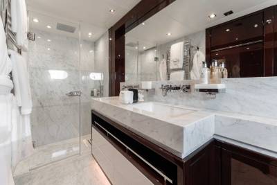 A modern and luxurious bathroom with a large vanity, a glass-enclosed shower, and various toiletry items displayed on the shelves.