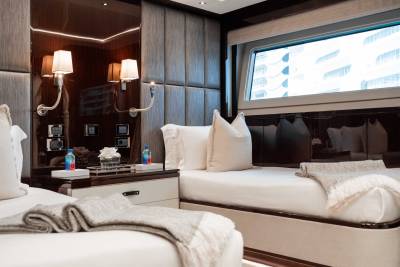 A cozy and luxurious bedroom with a large bed, plush white bedding, and dark wood paneled walls, complemented by a window offering a view of the outdoors.