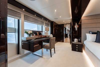 A luxurious and modern interior of a yacht, featuring a spacious cabin with large windows, a desk, and elegant furnishings.
