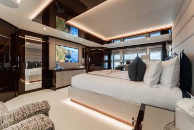 A luxurious and spacious bedroom with a large bed, plush furnishings, and floor-to-ceiling windows offering scenic views of the outdoors.