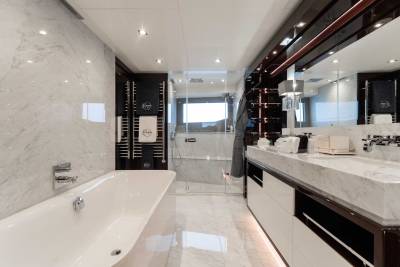 A modern, luxurious bathroom with a large bathtub, vanity with multiple drawers, and a glass-enclosed shower area, all set against a backdrop of sleek, minimalist design.
