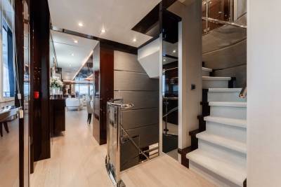 A modern and sleek interior design with a combination of dark and light tones, featuring built-in cabinets, a staircase, and a refrigerator in the background.
