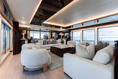 A luxurious and spacious living room with large windows offering a stunning view of the surrounding landscape, featuring plush white furniture, wooden accents, and a cozy atmosphere.