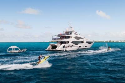 A large, luxurious yacht cruises across the vibrant turquoise waters, with a smaller boat trailing behind it, creating a dynamic and captivating scene.
