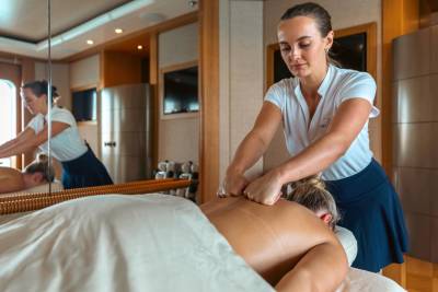 A skilled masseuse provides a relaxing back massage to a client on a luxurious yacht.