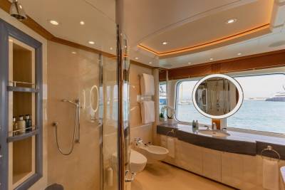 Luxurious yacht bathroom offers a spa-like experience with a spacious shower, bidet, and vanity overlooking the sparkling ocean.