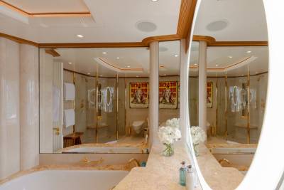 Luxurious marble and gold accents define this opulent bathroom, complete with a deep soaking tub and a glass-enclosed shower.