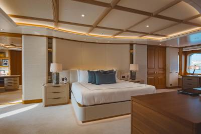 Luxurious yacht accommodations feature a spacious bedroom with elegant wooden accents and a serene view of the sea.