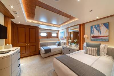 Luxurious twin beds with plush pillows and soft gray throws await in this elegantly appointed yacht cabin.