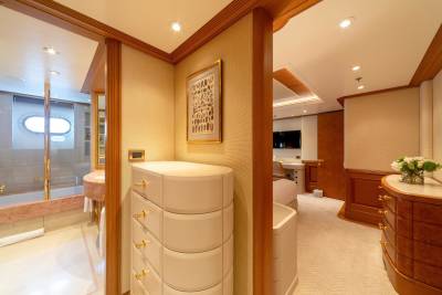 Luxurious yacht interiors feature a serene bathroom with a porthole window and a spacious bedroom with elegant wood finishes.