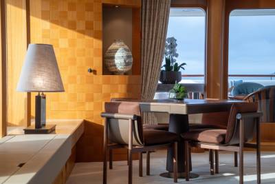 Luxurious yacht interiors feature warm wood paneling, plush seating, and elegant decorative pieces with ocean views.