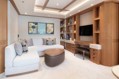 This elegant yacht lounge features a plush sectional sofa, a stylish wooden coffee table, and a built-in entertainment center.