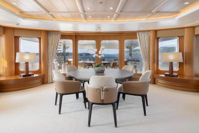 Dine with breathtaking ocean views from this elegant yacht dining room, featuring a circular table and plush seating.