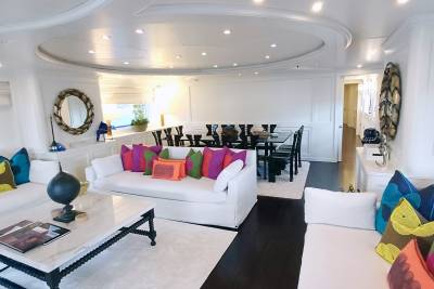 Luxurious white sofas and a sleek dining set create a sophisticated ambiance aboard this opulent yacht.