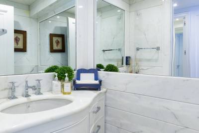 A luxurious marble bathroom features a double vanity with chrome fixtures and decorative seashell art.