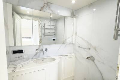 A luxurious bathroom features a marble vanity with a sleek sink and a mirrored medicine cabinet reflecting a heated towel rack.