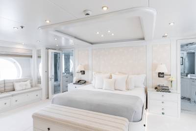 Luxurious white bedding and a palm-print headboard create a serene retreat in this elegant yacht stateroom.
