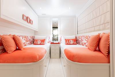 Coral accents and playful "Aloha" pillows create a vibrant and inviting twin cabin.