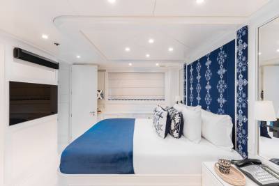 A luxurious bedroom features a plush bed adorned with decorative pillows and a vibrant blue throw, set against a patterned headboard.
