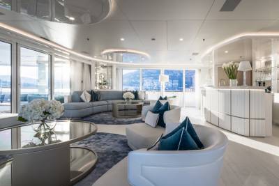 Luxurious yacht interiors feature a curved sofa and bar area with stunning ocean views.