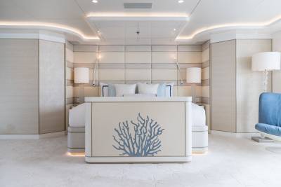 Luxurious yacht bedroom features a coral-adorned bed and plush white carpeting.
