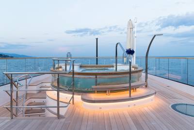 Relax in the illuminated jacuzzi on the deck of this luxurious yacht as the sun sets over the tranquil sea.