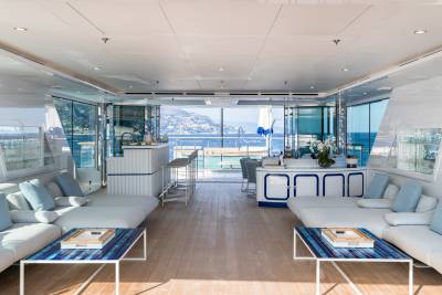 Luxurious yacht interiors open onto a stunning Mediterranean coastline with a sparkling blue sea.