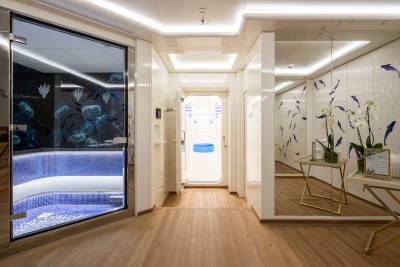 Step into a serene aquatic-themed spa area with a glass-enclosed pool and elegant mirrored walls.