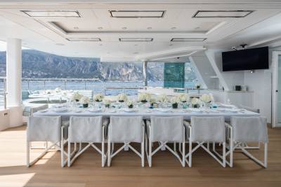 A beautifully set dining table on a yacht offers a stunning view of the Mediterranean coast.