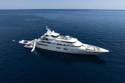A luxurious white superyacht with a waterslide and pool floats serenely on the deep blue ocean.
