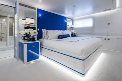 Luxurious yacht bedroom features a striking blue headboard, crisp white bedding, and elegant mirrored nightstands.