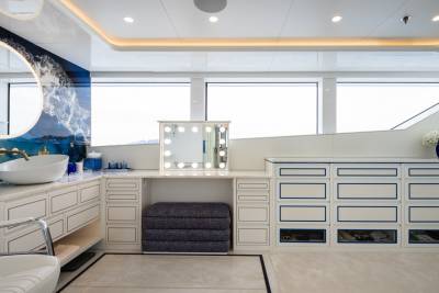 A luxurious vanity area with a large oval mirror and ample storage is bathed in natural light from expansive windows.