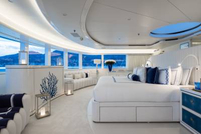 Luxurious yacht bedroom offers stunning ocean views and elegant white and blue decor.