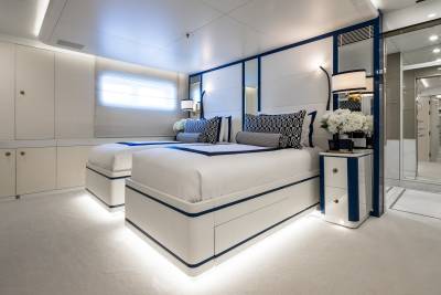 Luxurious twin beds with crisp white linens and elegant navy accents create a serene retreat in this yacht cabin.