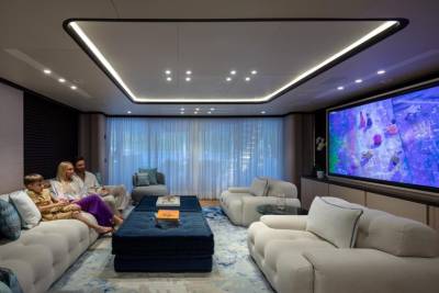 A family enjoys a movie night in a luxurious living room aboard a yacht.