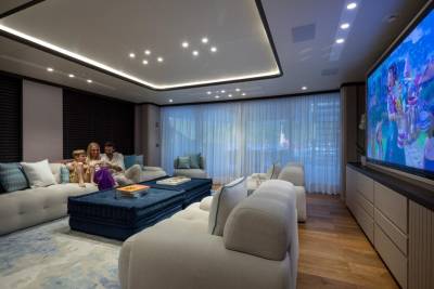 A family enjoys a movie night in a luxurious, modern living room aboard a yacht.