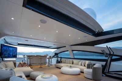 Luxurious yacht deck offers a stunning view with comfortable seating, a bar, and exercise equipment for ultimate relaxation and recreation.