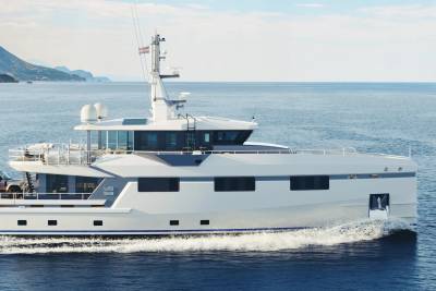 A sleek white yacht cuts through the calm blue sea, with a mountainous coastline visible in the distance.