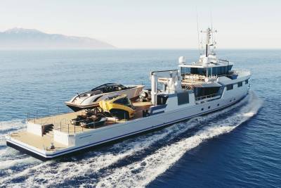 A sleek yacht support vessel cruises through calm blue waters, carrying a luxury tender, a submersible, and two jet skis.