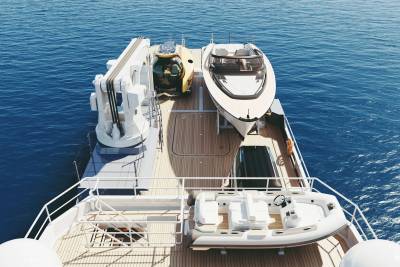 A luxury yacht carries a submersible, a speed boat, and a tender across the deep blue sea.