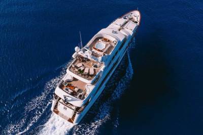 A luxurious white yacht glides through the deep blue ocean, leaving a trail of white foam in its wake.