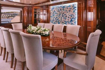 Luxurious yacht dining room features a polished wood table surrounded by plush chairs and a vibrant mosaic wall art.